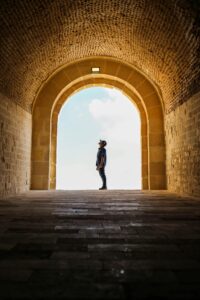 Man silhouetted in ancient stone archway exploring the historic architecture.