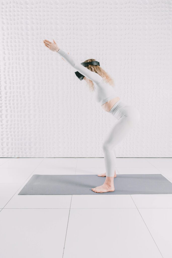 Adult woman practicing yoga with VR headset on a mat indoors.