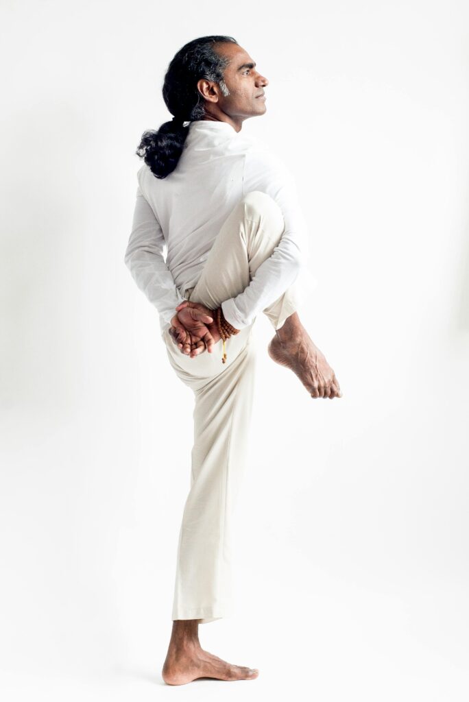 Side view of a man in a white outfit performing a standing yoga pose. Perfect for fitness and wellness themes.